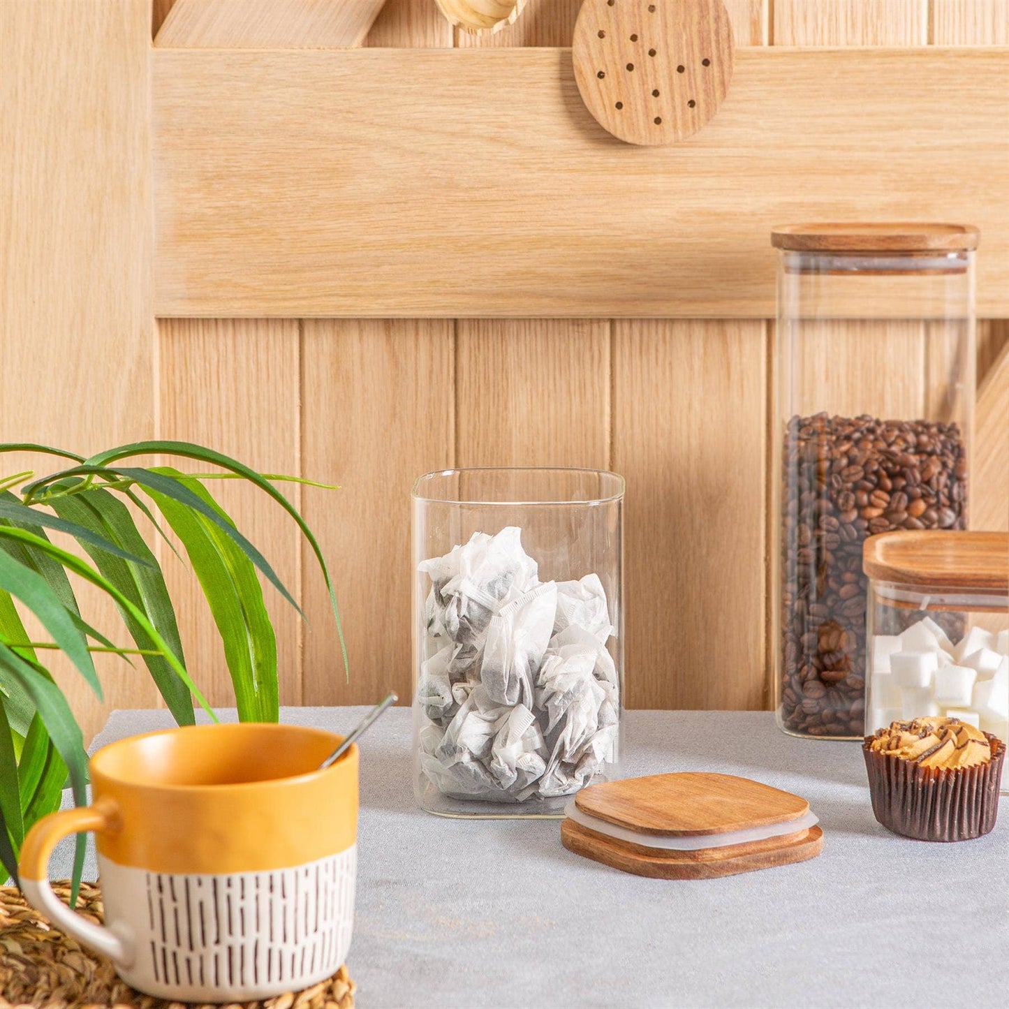 Firkantet oppbevaringskrukke i glass 1,1L fra argon tableware- Frontbilde av oppbevaringsglass oppå et bord. Slitesterkt og holdbar krukke i glass med akasietre lokk som holder maten fersk. Bilde av glasskrukke med teposer oppi